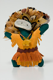 a small doll-like fetish with a headdress of feathers, beaded necklace, mask and dress made of leather.